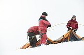 3 mountaineers in the swizz alpes, setting up the tent - on a hike/ climb in winter time, snowy surroundings
