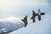 3 young people on winter holiday, with snowboards on the slope, in switzerland,