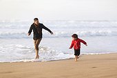 A 5 years old boy and his dad playing on the beach
