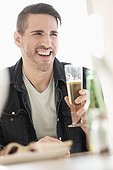 Man holding beer glass, laughing