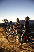 Two young women on motorcycles on empty road