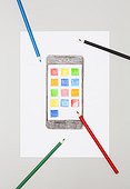 Drawn smartphone on a sheet of paper surrounded by coloured pencils