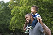 African American father carrying son outdoors