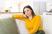 Portrait of thoughtful caucasian woman sitting on couch on in living room at home, copy space