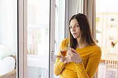Portrait of thoughtful caucasian woman holding tea cup by window in living room at home, copy space