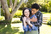 Happy diverse couple embracing in sunny garden, copy space