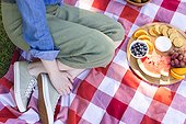 Caucasian woman sitting on blanket and having picnic in sunny garden, copy space
