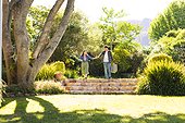 Happy diverse couple walking, holding hands and holding picnic basket in sunny garden, copy space