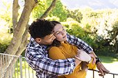 Happy diverse couple embracing and looking side in sunny garden, copy space