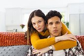 Portrait of happy diverse couple embracing on couch at home, copy space