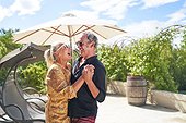 Happy, carefree senior couple laughing and dancing on summer patio