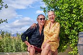 Portrait happy, carefree senior couple laughing on sunny summer patio