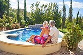 Senior couple relaxing at sunny summer swimming pool