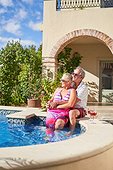 Carefree senior couple relaxing at swimming pool on villa patio