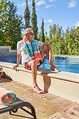 Senior man relaxing at sunny summer swimming pool
