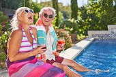 Portrait happy, carefree senior couple laughing at summer swimming pool