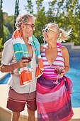 Happy senior couple drinking cocktails at summer poolside