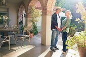 Happy senior couple holding hands on sunny villa patio