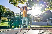 Carefree girl jumping on trampoline in sunny backyard