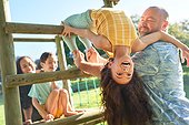 Father holding daughter upside-down, playing in sunny backyard