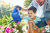 Portrait happy boy with Down Syndrome watering flowers with father