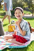 Portrait cute boy with Down Syndrome on picnic blanket in park