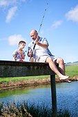 Father teaching son with Down Syndrome fishing on summer dock