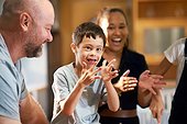Portrait happy boy with Down Syndrome clapping with family