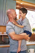 Father holding happy, cute son with Down Syndrome in kitchen
