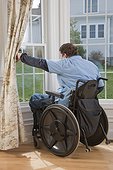 Man with spinal cord injury in a wheelchair looking out the window of his accessible home