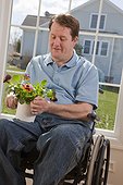 Man with spinal cord injury in a wheelchair arranging flowers in his home