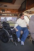 Man with spinal cord injury getting into the driver's seat from his wheelchair in accessible van