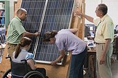 Engineering students examining photovoltaic panel's structural design and mounting