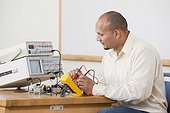 Engineering using multimeter probes to measure circuit characteristics in lab experiment in a classroom