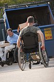 Men in wheelchairs moving trash to the dumpster