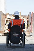 Facilities engineer in a wheelchair with spinal cord injury approaching commercial trash dumpster