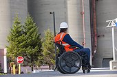 Facilities engineer in a wheelchair studying outdoor bulk storage tanks