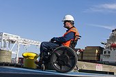 Transportation engineer in a wheelchair inspecting shipping containers at shipping port