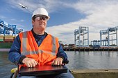Transportation engineer in wheelchair with a laptop at shipping port