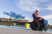 Transportation engineer in wheelchair passing bollard at shipping port