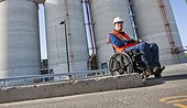Facilities engineer in wheelchair inspecting outdoor bulk storage tanks