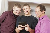 Three brothers reading a digital tablet