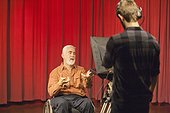 Man with muscular dystrophy and diabetes speaking on a camera in a TV studio