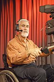 Man in wheelchair with muscular dystrophy using a TV camera in studio