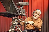 Man in wheelchair with muscular dystrophy using a TV camera and a teleprompter in studio