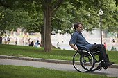 Man with spinal cord injury in a wheelchair on path in a public park