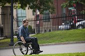 Man with spinal cord injury in a wheelchair on path in a public park