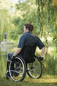 Man with spinal cord injury in a wheelchair enjoying the pond in public park