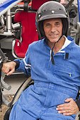 Disabled race car driver with spinal cord injury in wheelchair with his modified race car