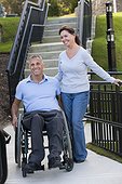 Woman standing with husband in wheelchair with spinal cord injury on accessible ramp